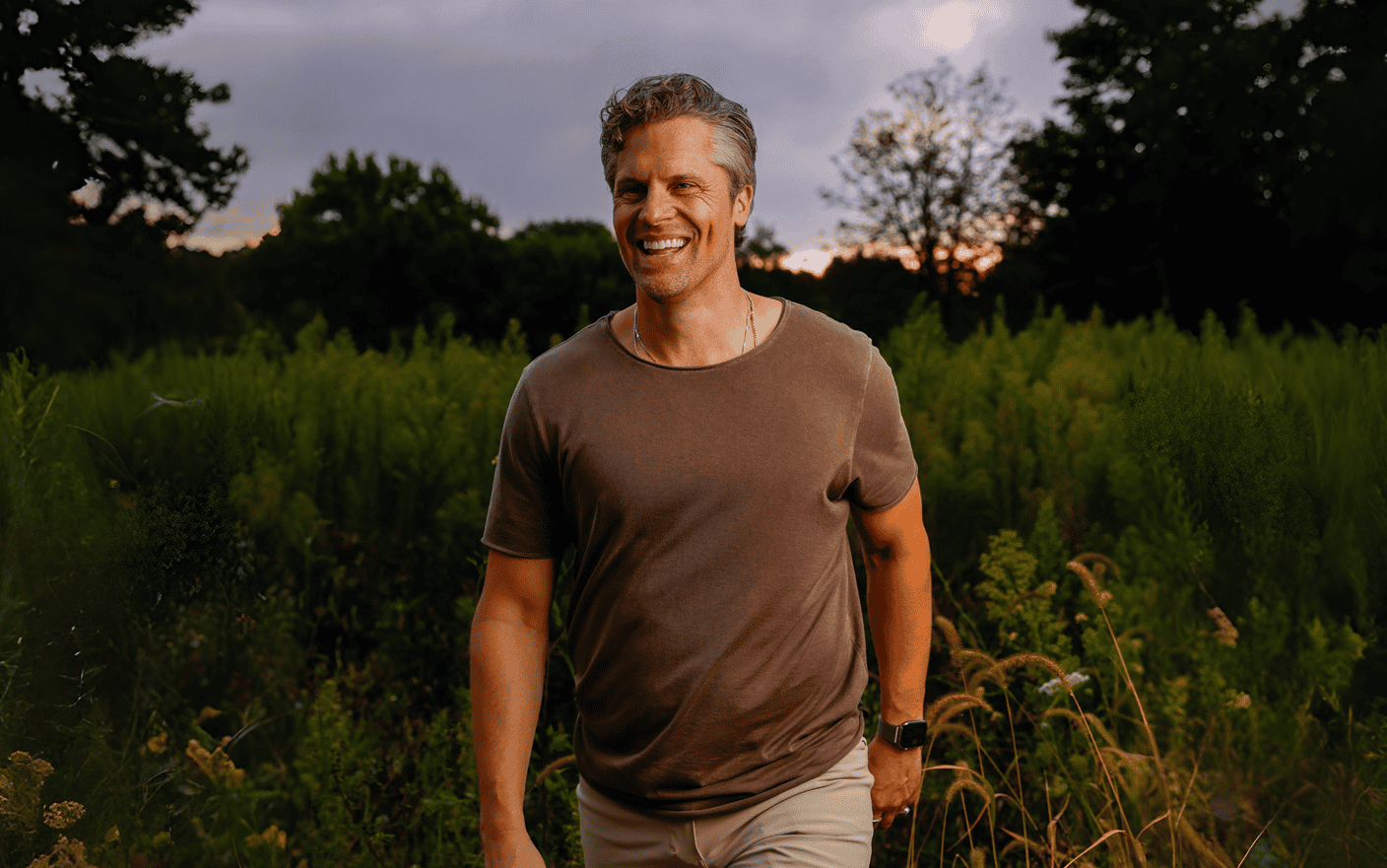 Ben Katt walking through a nature field at dusk, symbolizing the journey to wholeness and reclaimed aliveness.