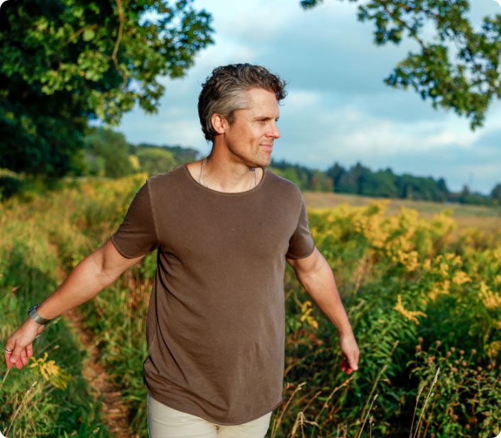 A man practicing mindful walking outdoors in a lush green field, embracing calmness and presence.